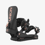 Black snowboard bindings with rose gold branding on a white background