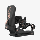 Black snowboard bindings with rose gold branding on a white background
